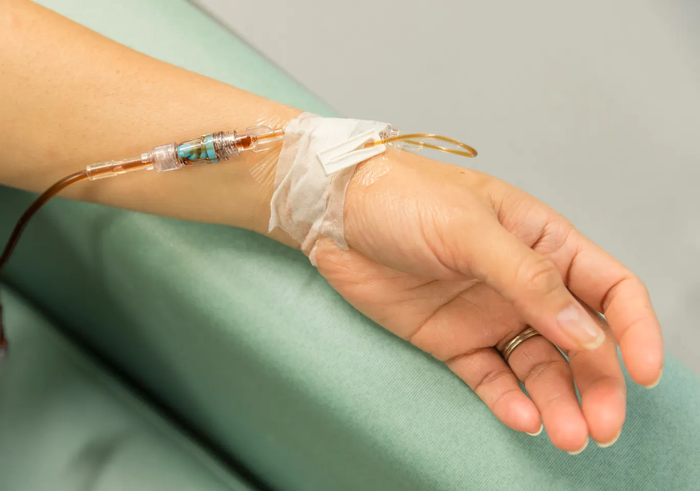 Kroplówki witaminowe Piastów: dłoń z wenflonem i linią infuzyjną na podkładzie